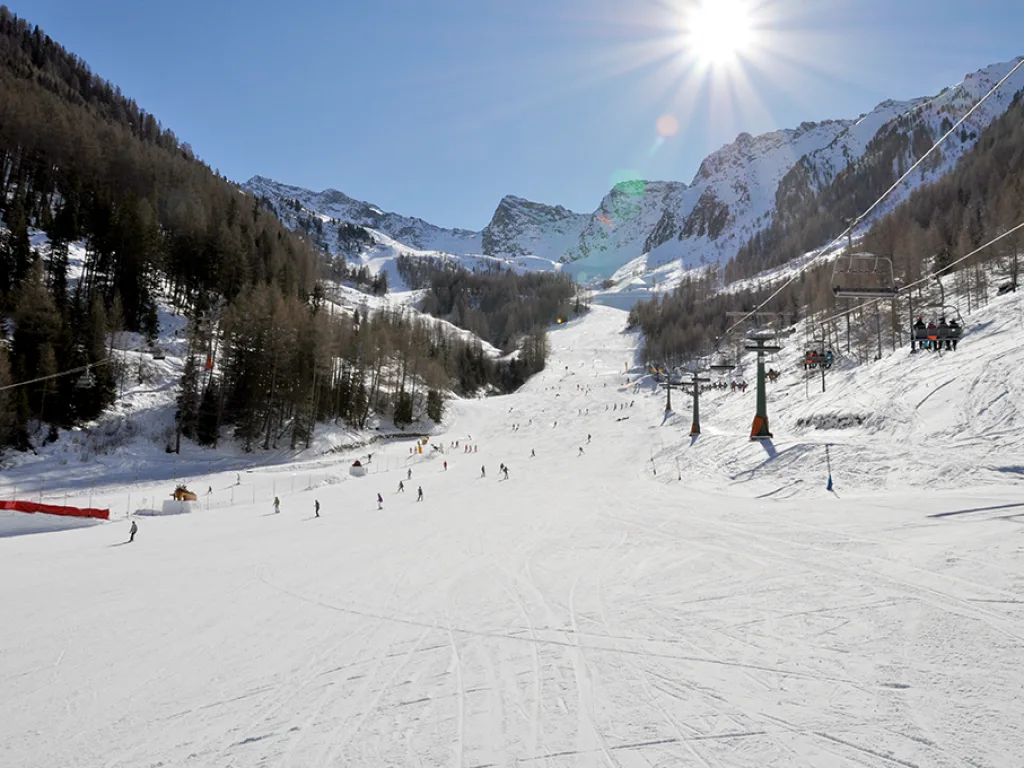 Blick gegen die Sonne über die Piste ins Tal.
